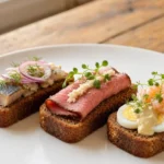 Smørrebrød – Dänische belegte Roggenbrote mit abwechslungsreichen Belägen wie eingelegtem Hering, Roastbeef, Ei, Krabben oder Remoulade.