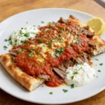 İskender Kebab – Bursa-Spezialität aus dünnen Döner-Scheiben auf Pide-Brotstücken, übergossen mit Tomatensauce und geschmolzener Butter, oft ergänzt durch Joghurt.